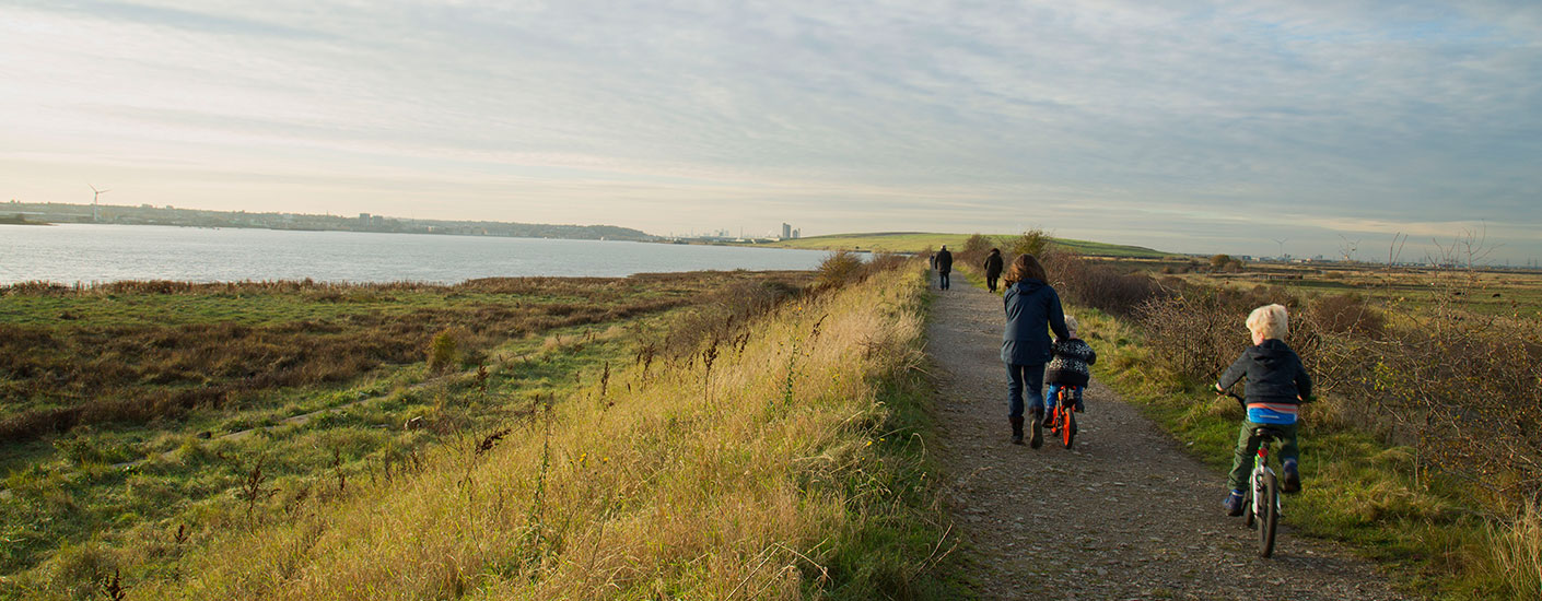 Family cycling and walking together in RSPB Rainham Marshes